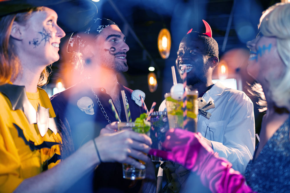 junge Leute auf einer Kostüm Party wie beim Fasching oder Halloween, die mit ihren Cocktails anstoßen